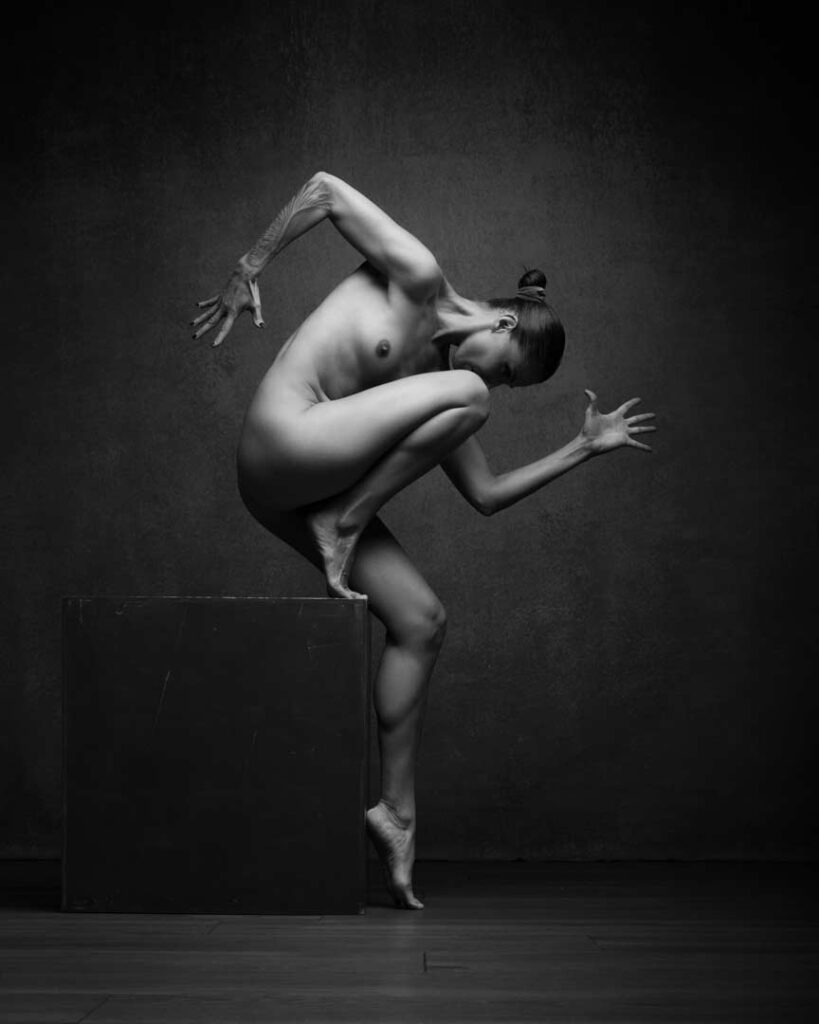 Sculptural nude pose, dancer-like figure on a cube