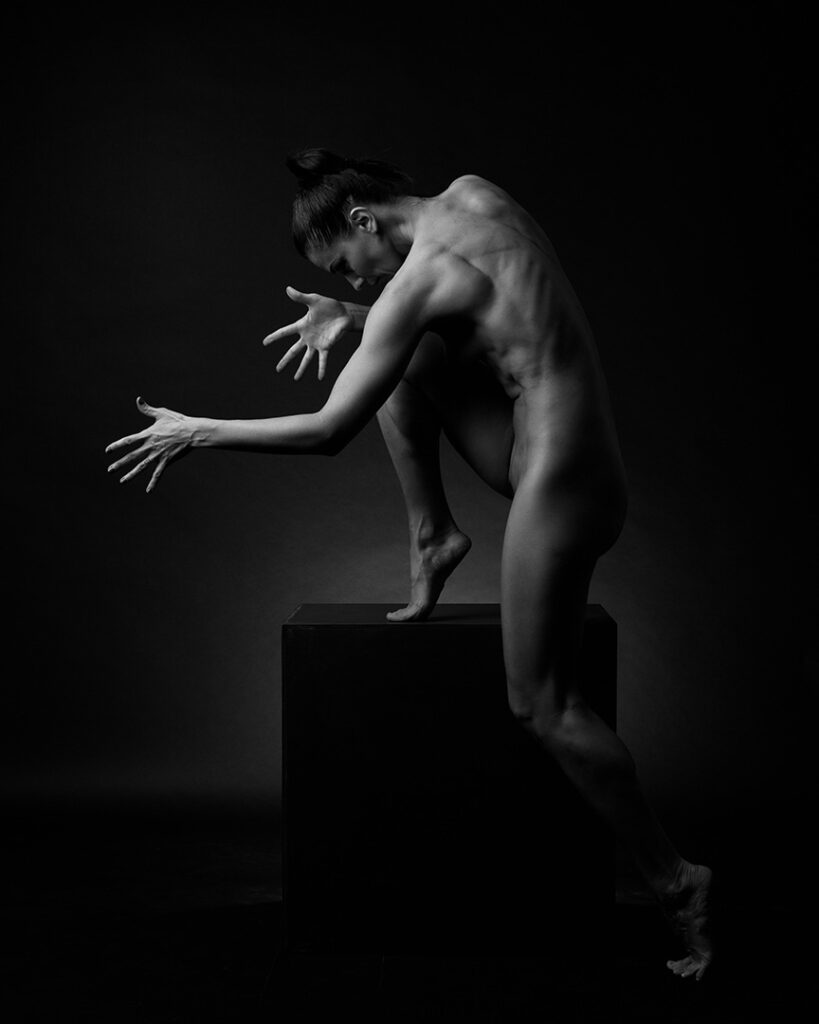 Nude woman in expressive pose with outstretched hands