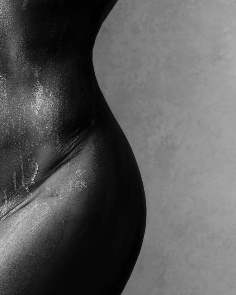 Close-up of a woman’s torso painted with oil, glistening
