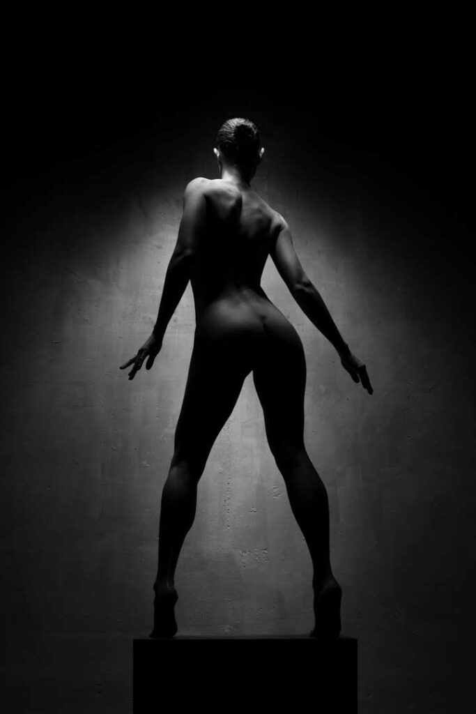 Artistic nude silhouette of a woman standing in dramatic lighting
