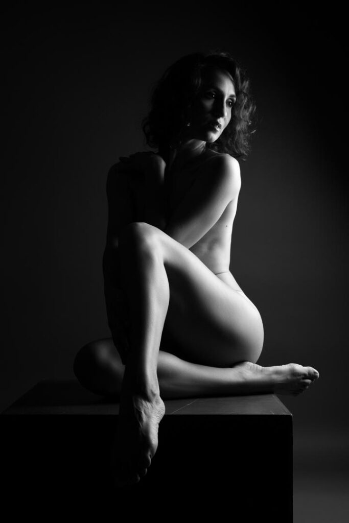 Nude woman in seated pose, illuminated from the side